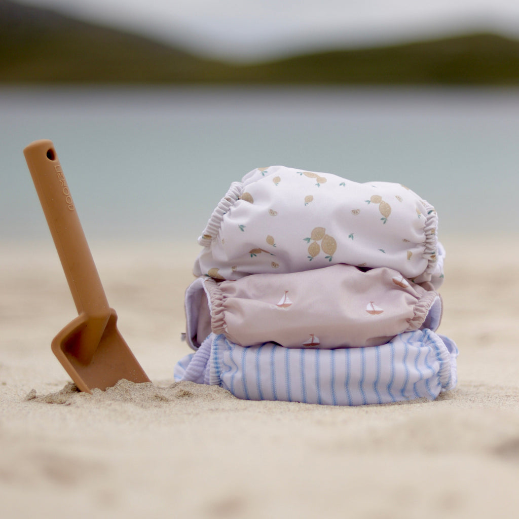 reusable swim nappies stacked on sand